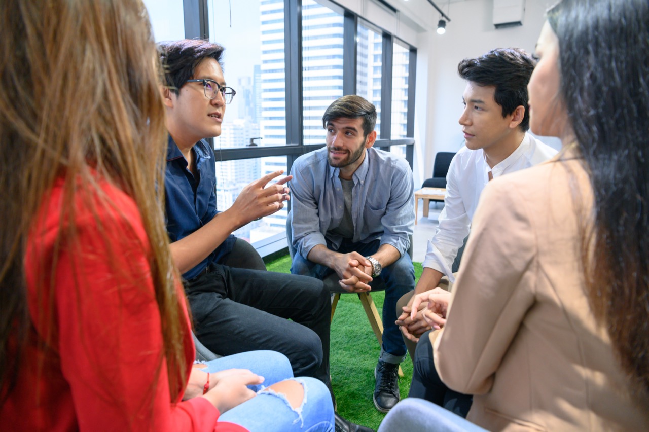 Psychotherapist Inquiring About Symptoms Occurring Within Mind From Patients With Mental Health Problems In Hospital. Group Psychotherapy For Support And Helping Worried Man To Change Negative Mindset AdobeStock 308994904 Large